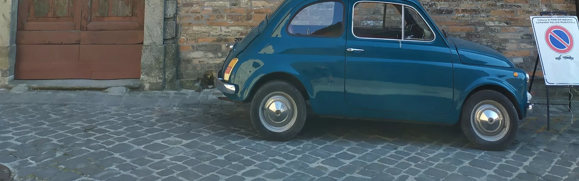 Fiat blu parcheggiata davanti a un edificio in mattoni in Italia